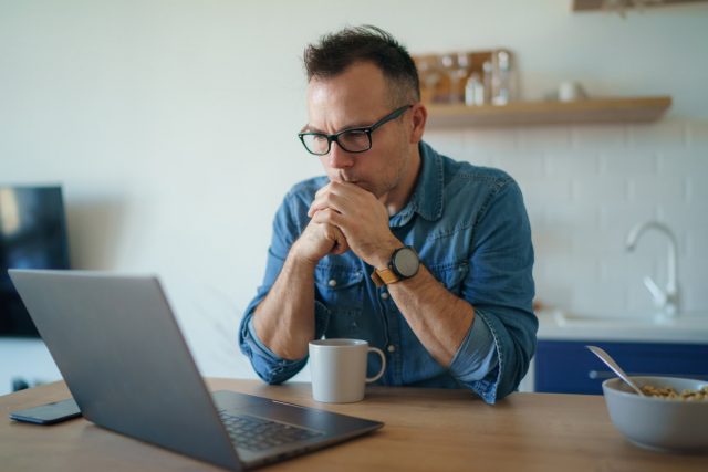 man looking at computer to review the facts about roofing insurance