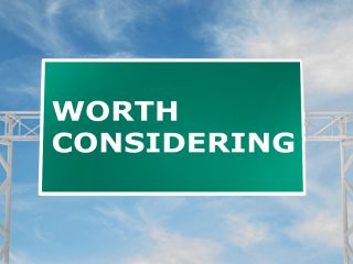green highway sign with "worth considering" written about the pros and cons of asphalt roofing