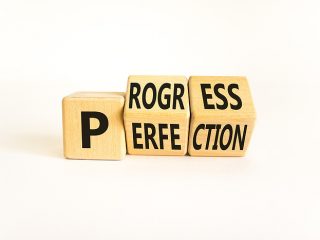 Blocks with letters on them spelling out the words progress and perfection.