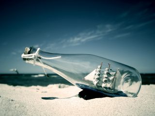 Photo Of A Model Ship In A Bottle On A Beach