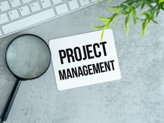 “Project Management” Coaster With Magnifying Glass And Keyboard In Background.